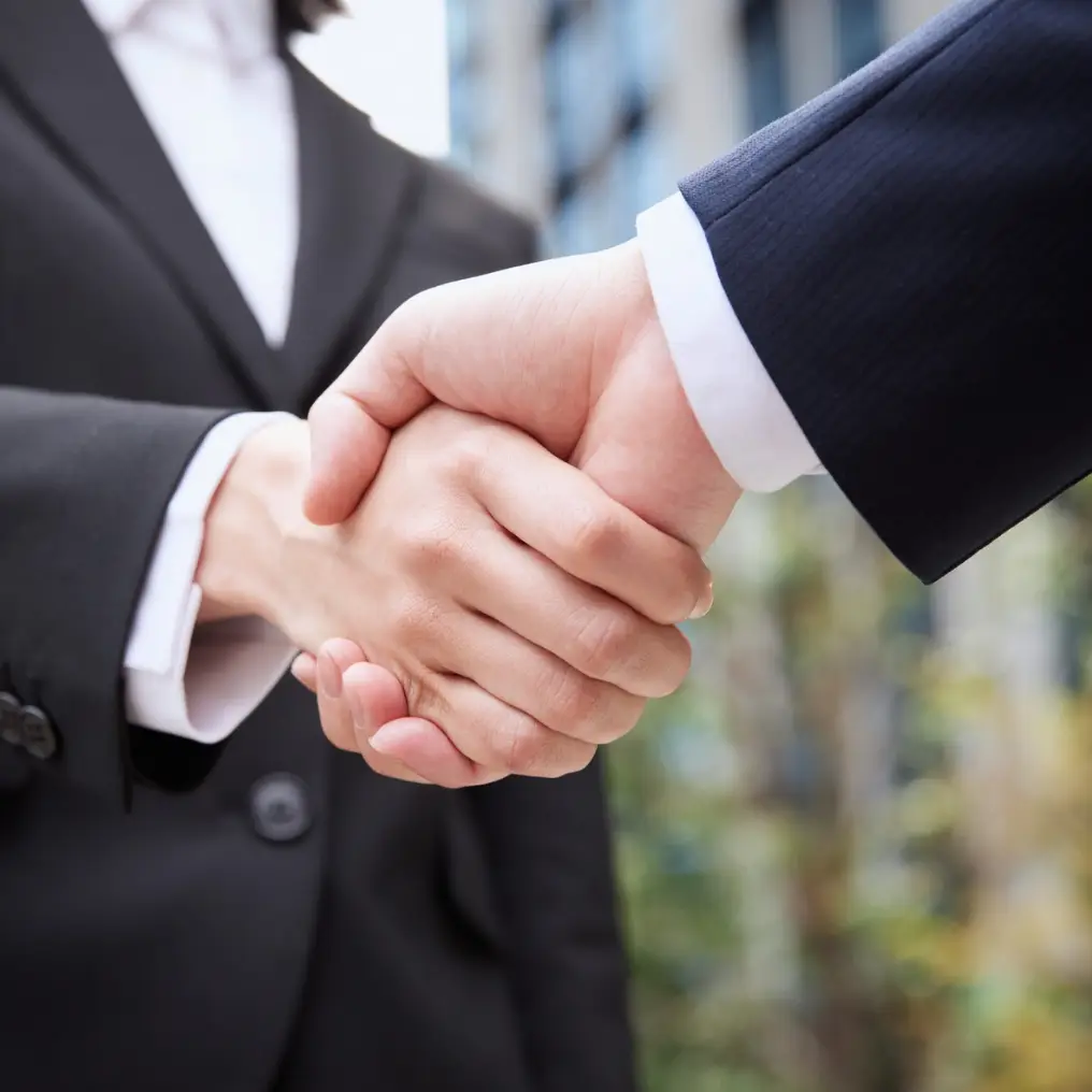 Two professionals shaking hands in a workplace setting