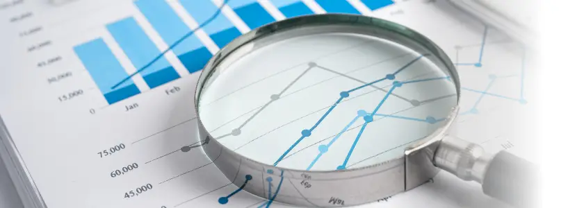 Magnifying glass examining assessment data and performance charts